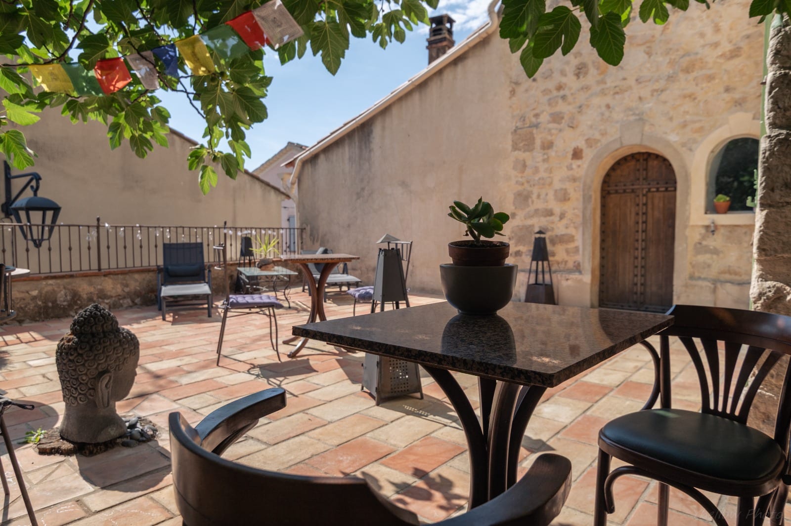 Coin repas extérieur entouré de plantes sur la terrasse du Couvent des Pallières