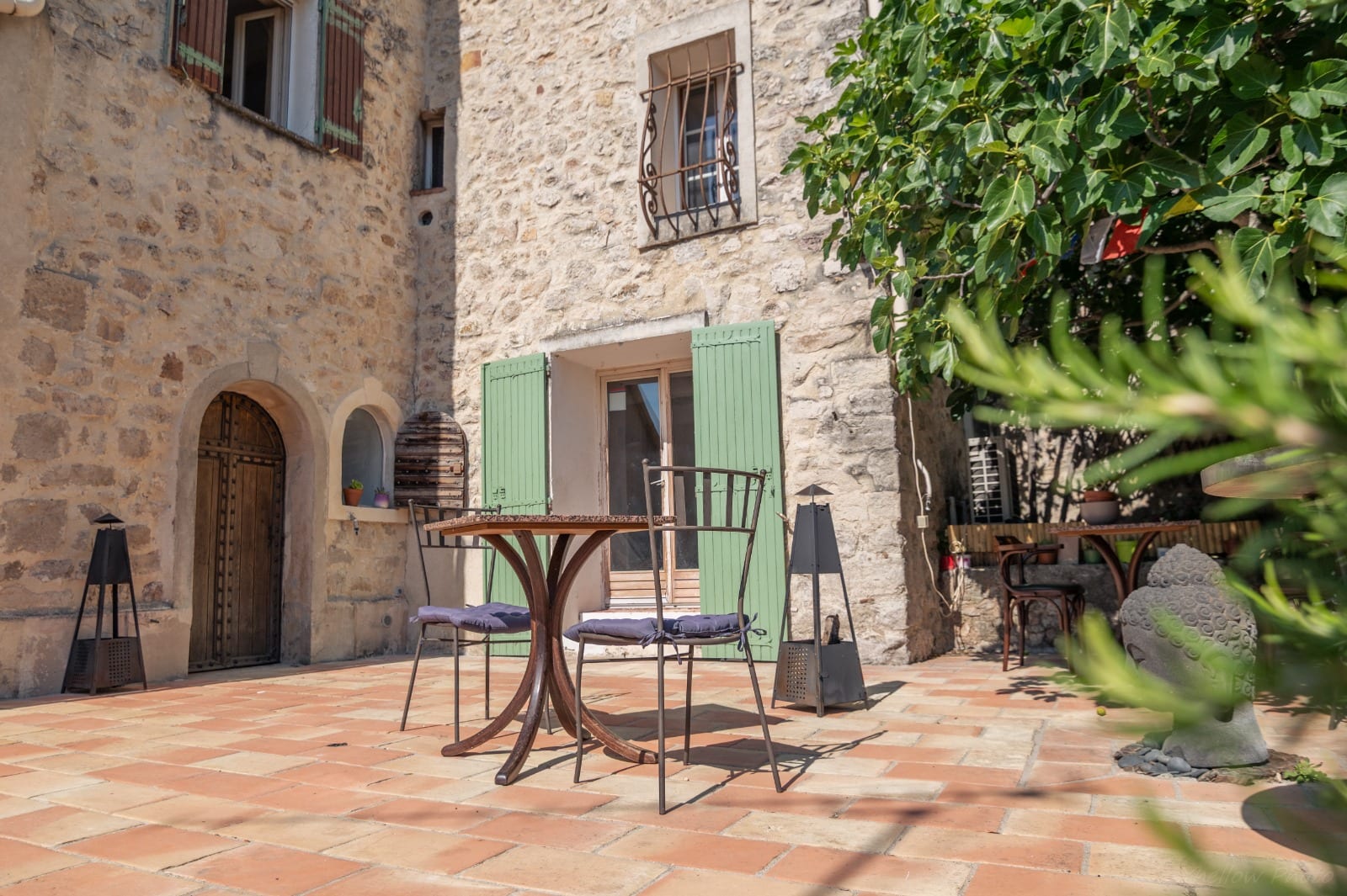 Terrasse provençale avec porte à volets verts et table bistrot au Couvent des Pallières